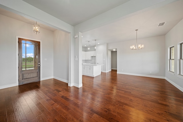 foyer entrance featuring dark wood-type flooring and a notable chandelier