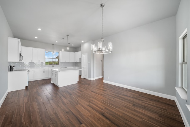 kitchen featuring hanging light fixtures, a center island, an inviting chandelier, white cabinetry, and dark hardwood / wood-style flooring