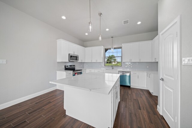 kitchen featuring appliances with stainless steel finishes, white cabinets, a center island, and dark hardwood / wood-style flooring