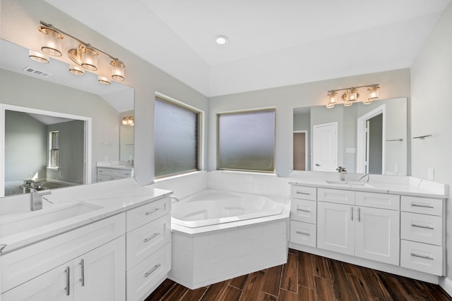 bathroom with vanity, hardwood / wood-style floors, and tiled tub