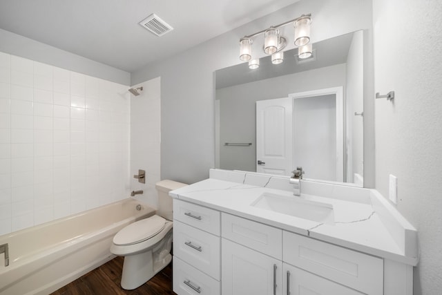 full bathroom with toilet, tiled shower / bath, hardwood / wood-style flooring, and vanity