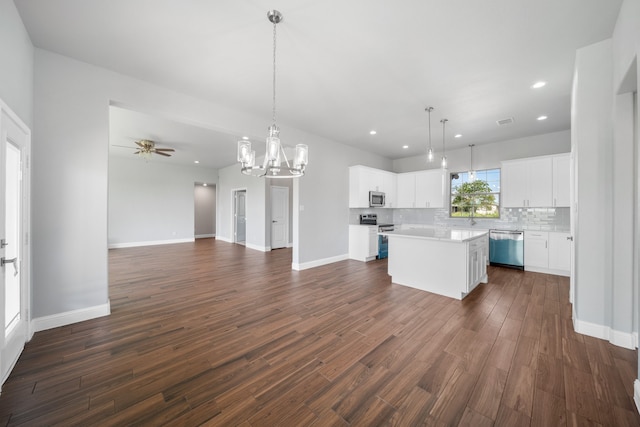 kitchen with appliances with stainless steel finishes, dark wood-type flooring, a center island, and white cabinets