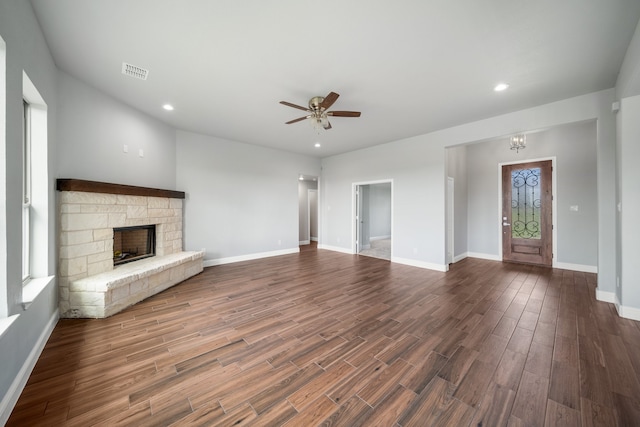 unfurnished living room with ceiling fan, a stone fireplace, and dark hardwood / wood-style floors