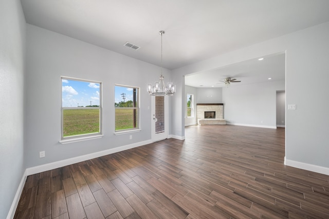 unfurnished living room with dark wood-type flooring, a fireplace, and ceiling fan with notable chandelier