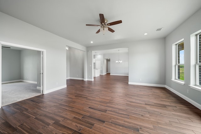 unfurnished living room featuring ceiling fan with notable chandelier and dark hardwood / wood-style floors