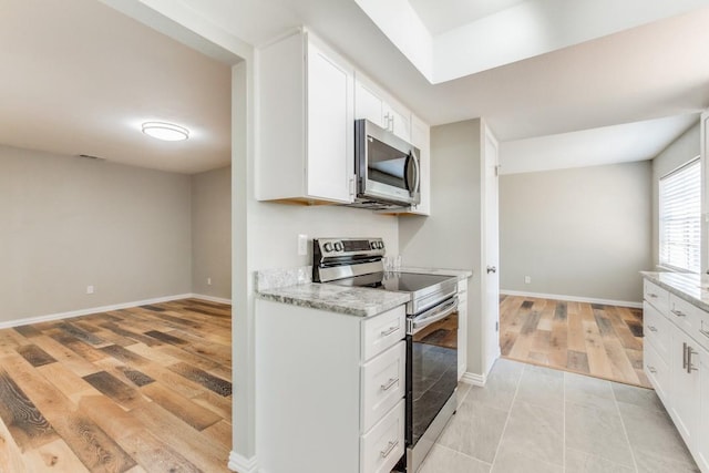 kitchen featuring white cabinetry, light hardwood / wood-style flooring, stainless steel appliances, and light stone counters