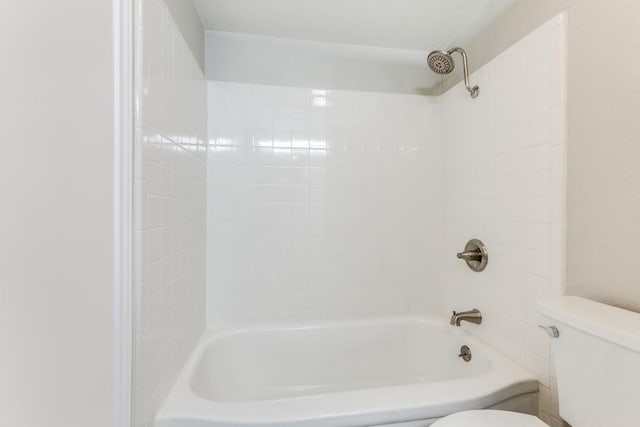 bathroom with toilet and tiled shower / bath