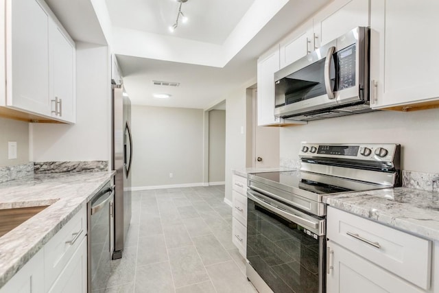 kitchen with white cabinets, light tile patterned flooring, light stone countertops, and appliances with stainless steel finishes