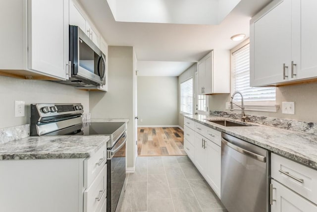 kitchen featuring light stone counters, sink, white cabinets, and stainless steel appliances