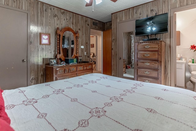 bedroom featuring ceiling fan, wooden walls, and connected bathroom