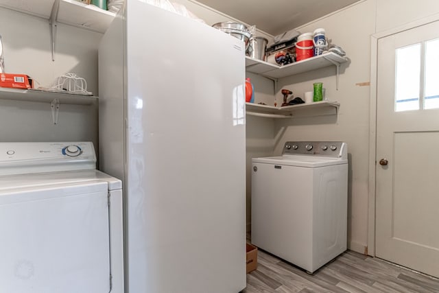 clothes washing area featuring light hardwood / wood-style floors and washer and clothes dryer