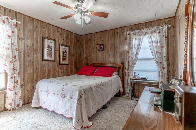 carpeted bedroom with wood walls and ceiling fan