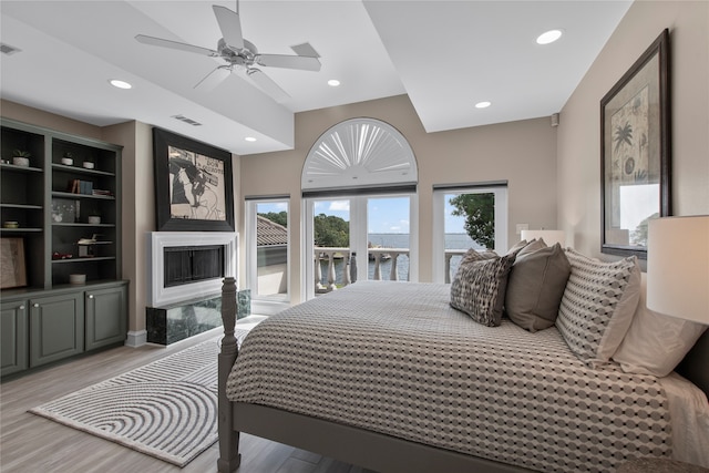 bedroom with light hardwood / wood-style flooring, ceiling fan, a high end fireplace, and access to outside