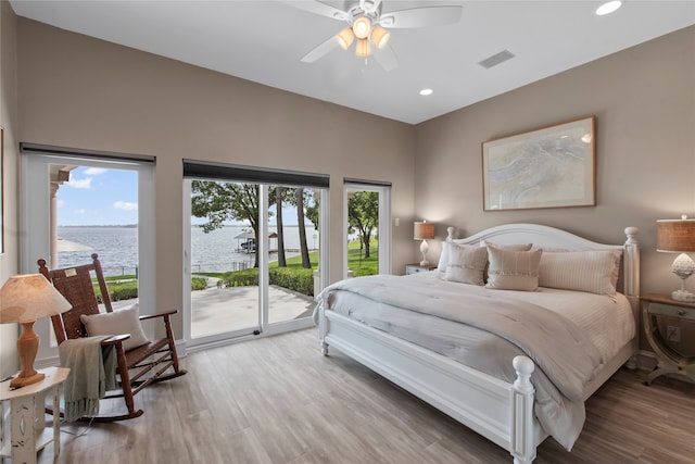 bedroom with ceiling fan, a water view, hardwood / wood-style flooring, and access to outside