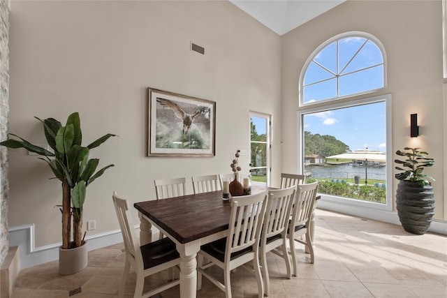 tiled dining room featuring high vaulted ceiling and a water view