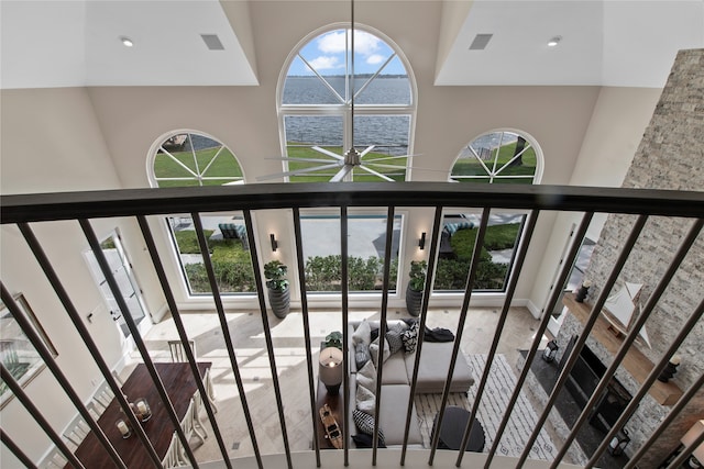 staircase with a wealth of natural light, ceiling fan, a water view, and a towering ceiling