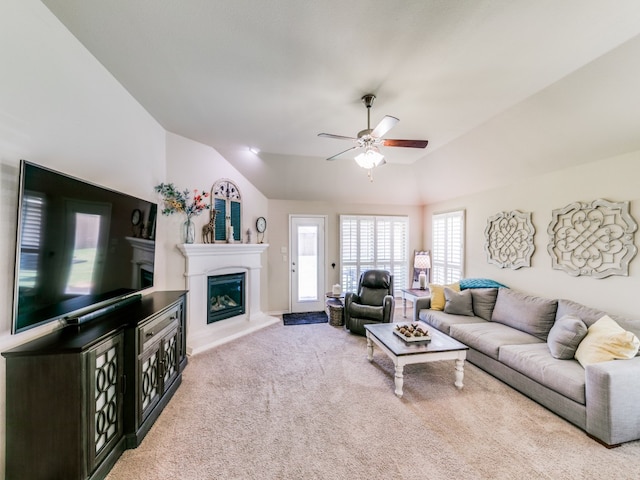 carpeted living room with ceiling fan and vaulted ceiling