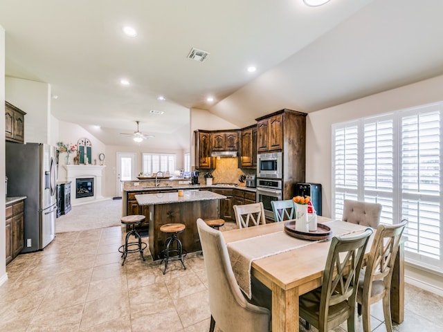 tiled dining space with sink, ceiling fan, lofted ceiling, and a wealth of natural light