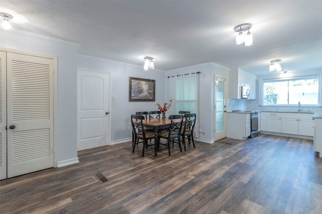 dining space featuring sink, crown molding, and dark wood-type flooring