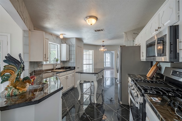 kitchen featuring backsplash, appliances with stainless steel finishes, a textured ceiling, and white cabinetry