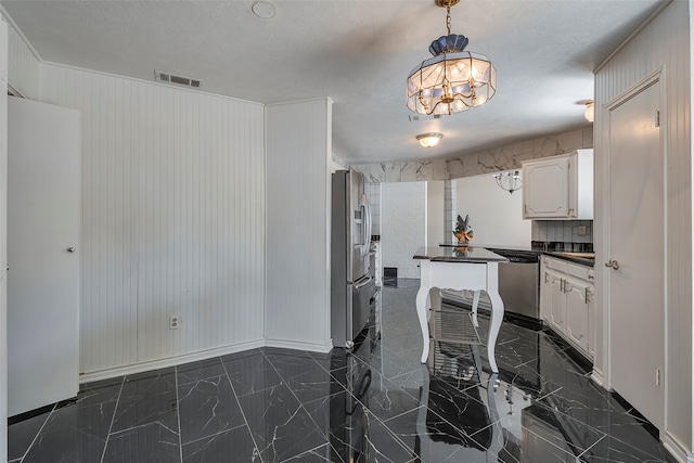 kitchen with a textured ceiling, white cabinets, stainless steel appliances, and an inviting chandelier