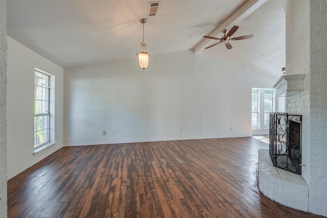 unfurnished living room featuring lofted ceiling with beams, dark wood-type flooring, plenty of natural light, and a brick fireplace