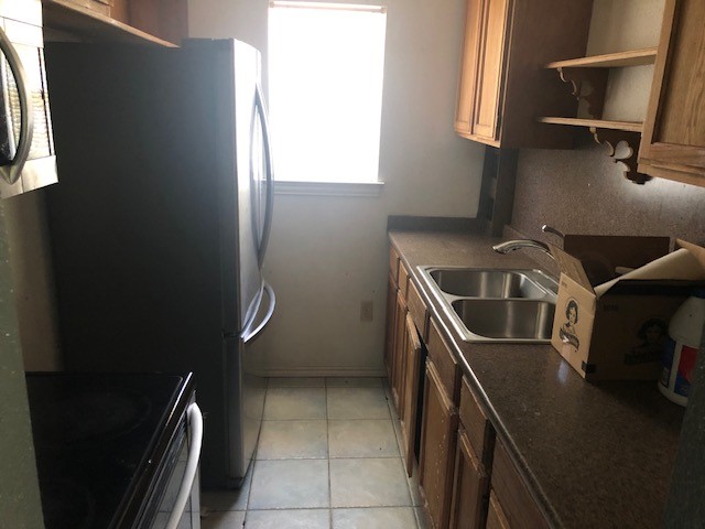 kitchen with sink, stainless steel refrigerator, range, and light tile patterned flooring