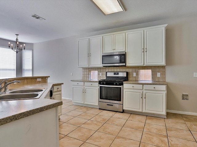 kitchen with light tile patterned flooring, sink, backsplash, white cabinetry, and stainless steel appliances