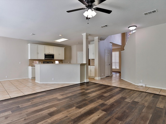 kitchen with ceiling fan, white cabinets, light hardwood / wood-style floors, decorative columns, and backsplash