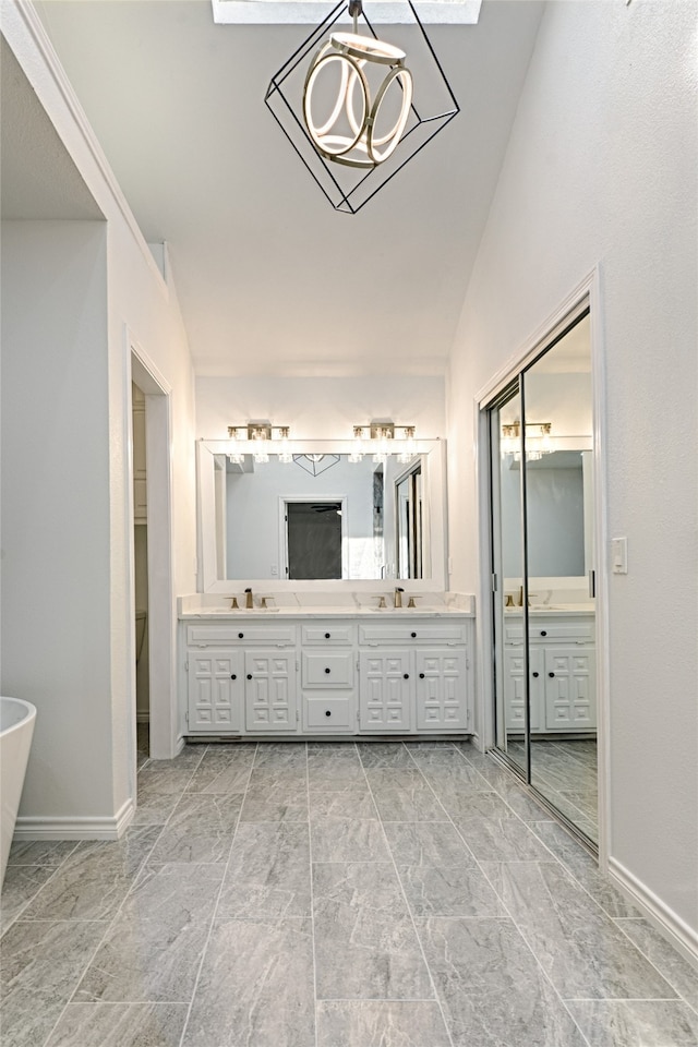 bathroom featuring vanity, vaulted ceiling with skylight, and a tub