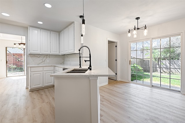 kitchen featuring decorative backsplash, decorative light fixtures, a chandelier, white cabinets, and light hardwood / wood-style floors