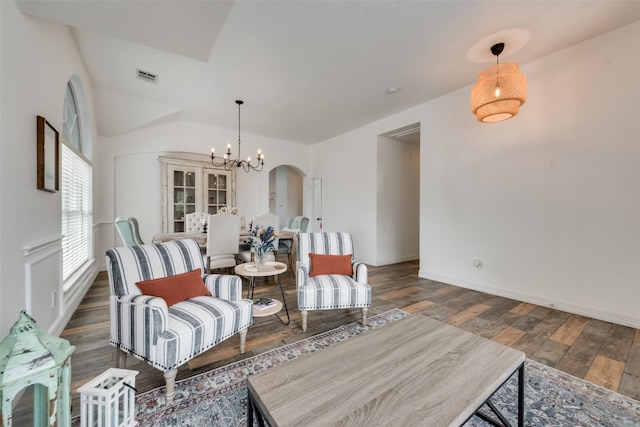 living area with a notable chandelier, vaulted ceiling, and dark hardwood / wood-style floors