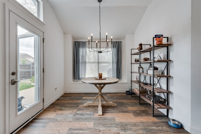 dining space with dark hardwood / wood-style floors, vaulted ceiling, and a notable chandelier