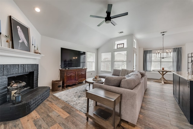 living room featuring a healthy amount of sunlight, wood-type flooring, ceiling fan with notable chandelier, and a fireplace