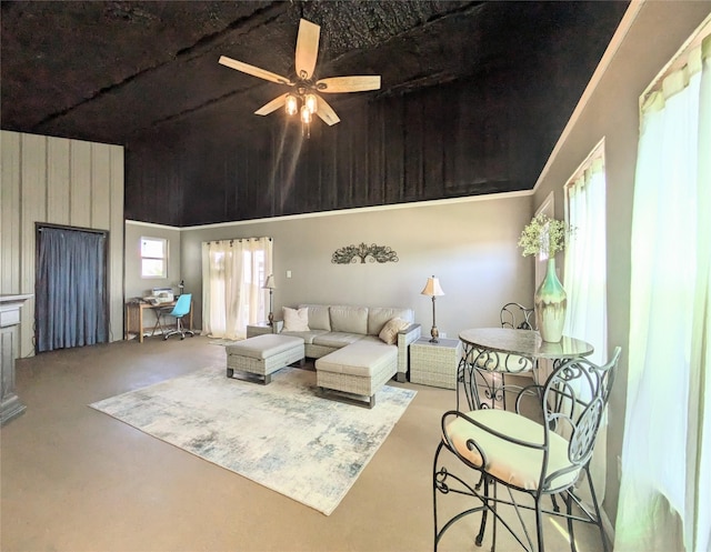 living room with ceiling fan, a high ceiling, and wooden walls