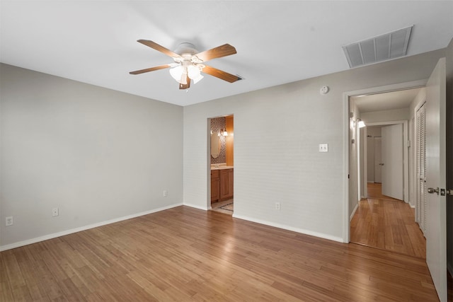 unfurnished bedroom featuring ensuite bathroom, hardwood / wood-style floors, and ceiling fan