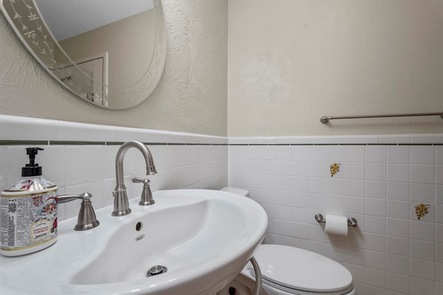 bathroom featuring sink, toilet, tasteful backsplash, and tile walls