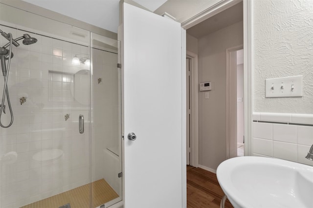 bathroom with a shower with shower door, sink, and hardwood / wood-style floors