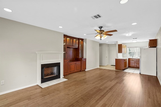 unfurnished living room with sink, light tile patterned floors, and ceiling fan