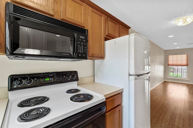 kitchen featuring range, hardwood / wood-style flooring, and white refrigerator