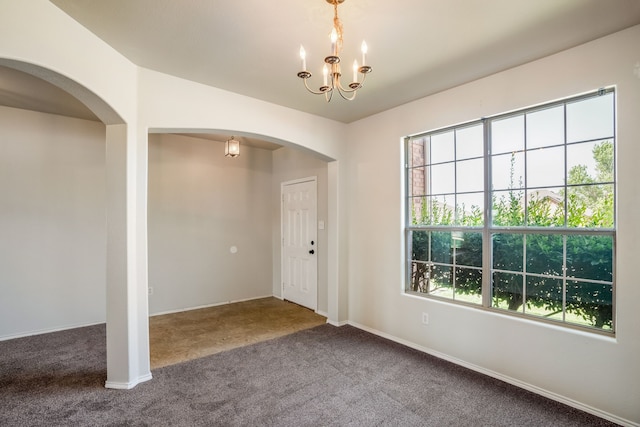 carpeted empty room featuring a chandelier