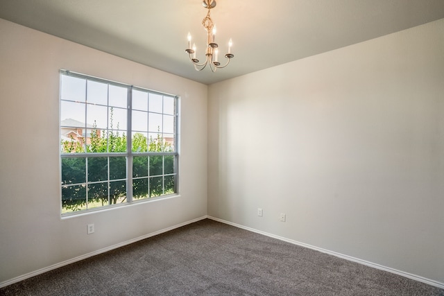 carpeted spare room featuring a notable chandelier