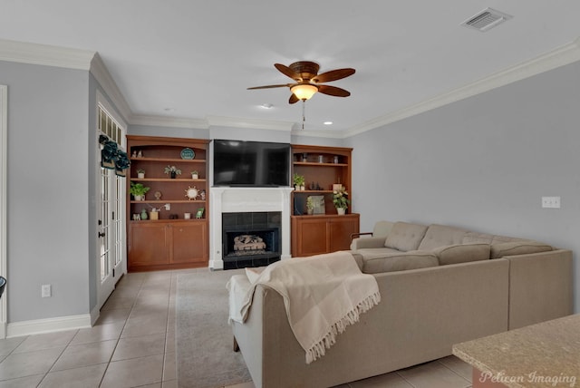 tiled living room with a tiled fireplace, ceiling fan, and ornamental molding