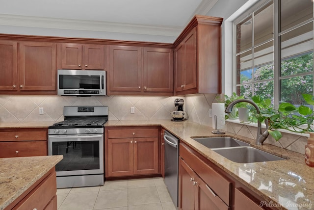 kitchen featuring appliances with stainless steel finishes, light stone counters, crown molding, sink, and light tile patterned floors