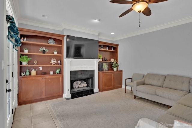 tiled living room with ceiling fan, ornamental molding, and a tiled fireplace