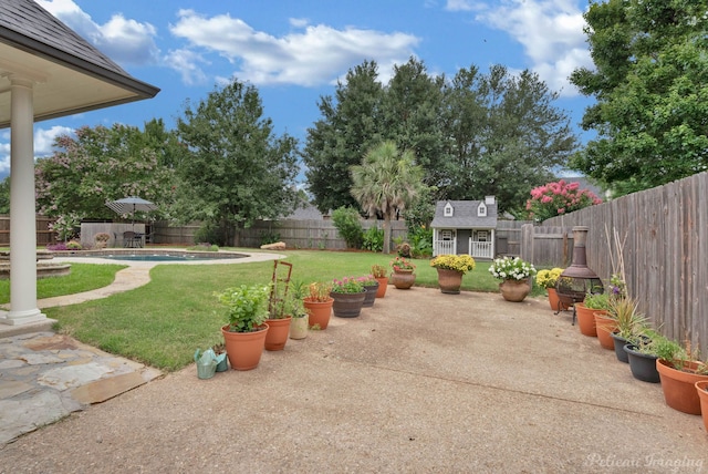 view of yard featuring a fenced in pool, a patio area, and an outdoor structure