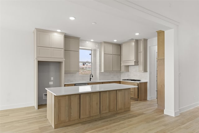 kitchen featuring light hardwood / wood-style flooring, backsplash, a center island, and sink