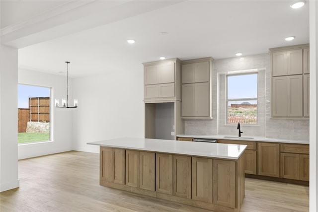 kitchen with a healthy amount of sunlight, light hardwood / wood-style floors, sink, and a kitchen island