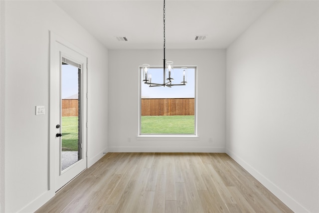 unfurnished dining area featuring light wood-type flooring and a notable chandelier