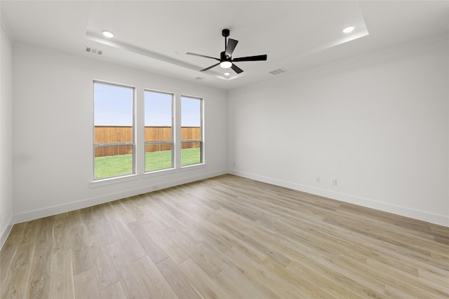 unfurnished room with ceiling fan, a tray ceiling, and light hardwood / wood-style floors